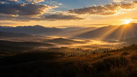 Sunrise and golden rays over a quiet mountain valley
