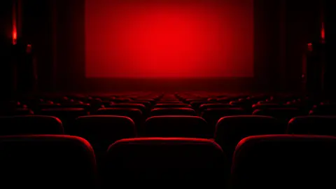 An empty movie theater lit by a red screen